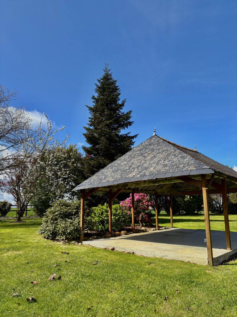 Vue sur le kiosque du domaine, avec les arbres en fleur et un beau ciel bleu